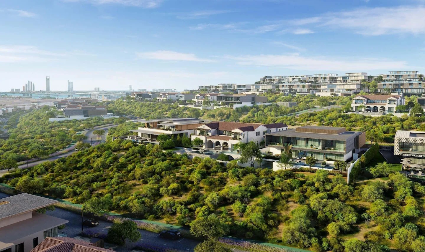 Aerial of a Modon Hudayriyat Island community in greenery with the Abu Dhabi skyline beyond