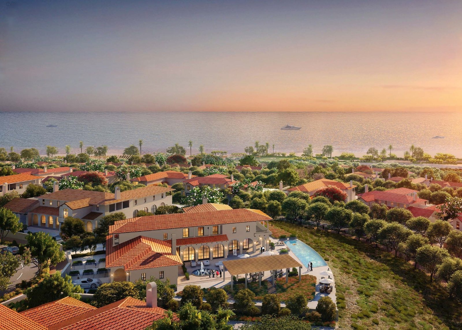 Sunset aerial across a Modon Hudayriyat community of Mediterranean-style villas with red tile roofs, set against the sea